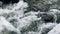 Rapids in river. Wet boulders in stormy water flow. Closeup foamy river rapid.