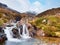 Rapids in small waterfall on stream, Higland in Scotland an early spring day. Snowy mountain peaks