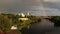 A rare event. Top view on rainbow in the blue sky over the city. Sandy beach at sunset. Bridge and beautiful churches.