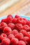 Rasberry in blue green dish on old vintage wooden table.