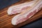 Rashers of Uncured Apple Smoked Bacon arranged on natural wooden cutting board