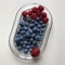 Raspberries, blueberries & a single strawberry atop a glass dish - VEGAN - VEGETARIAN