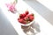 Raspberry berries in a glass vase on the kitchen table in the sun and shadows from objects, top view