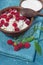 Raspberry branch with berries curd sour cream in earthenware on cloth blue background