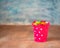 Raspberry bucket with polka dots with colored caramel on a brown wooden table