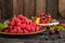 Raspberry, cherry, red currant, blackcurrant on a wooden plate against a dark background