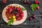 Raspberry, cherry, red currant, blackcurrant on a wooden plate against a dark background