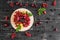 Raspberry, cherry, red currant, blackcurrant on a wooden plate against a dark background