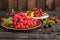 Raspberry, cherry, red currant, blackcurrant on a wooden plate against a dark background