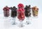 Raspberry, gooseberry, a big black blackberry, red currant and mulberry are located in clear glass on a light background