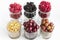 Raspberry, gooseberry, a big black blackberry, red currant and mulberry are located in clear glass on a light background