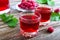 Raspberry liqueur in glass, fresh natural ripe organic berries and green leaves on a rustic wood background. Alcoholic flavored
