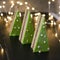 Raspberry-pistachio opera cake slices decorated with with green mirror glaze on black background lights. Pieces of cake look like