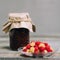 raspberry on a plate and glass jars with raspberry jam on a wooden table, home-made preparations, cooking, homemade desserts