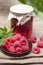 Raspberry preserve in glass jar and fresh raspberries