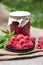 Raspberry preserve in glass jar and fresh raspberries