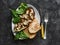 Ratatouille stuffed baked eggplant with mozzarella cheese, spinach and grilled bread on a dark background, top view