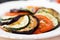 Ratatouille, vegetables cut on slices, eggplant, zucchini, tomatoes on plate
