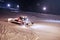 Ratrak removes snow from ski slope. Snowcat preparing a slope at night. Red snowcat levels the ski slope at night by the
