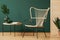 Rattan chandelier above wicker peacock chair in elegant interior with copy space and wooden screen on the empty green wall, concep