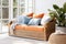 Rattan loveseat sofa with blue cushions and orange pillows and blanket. Scandinavian interior design