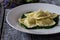 Ravioli stuffed with potatoes and carrots on a bed of borage puree with a sprinkling of Parmesan cheese and black pepper