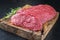 Raw angus roast beef with herbs on an old rustic wooden cutting board