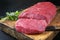 Raw angus roast beef with herbs on an old rustic wooden cutting board