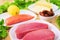 Raw appetizing fillet of tuna on a table with a yard of Greek salad with salmon and lemon cucumbers and tomatoes as well