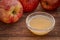 raw apple cider vinegar with mother - a small glass bowl with fresh red apples