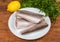 Raw Argentine hake carcasses on dish, lemon, parsley on rustic table