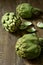 Raw artichokes on a wooden surface