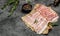 Raw bacon, bacon strips meat slice thin slicing pork fat meal on a dark background, ketogenic diet, place for text, top view