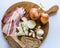 Raw bacon on cutting desk with onion and garlic and tomato behind.