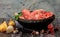 Raw beef bones in round clay bowl on wooden table decorated with vegetables and spices, vintage hunter knife. Beef selection for b