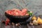 Raw beef bones in round clay bowl on wooden table decorated with vegetables and spices, vintage hunter knife. Beef selection for b