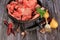Raw beef bones in round clay bowl on wooden table decorated with vegetables and spices, vintage hunter knife. Beef selection for b