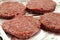 Raw beef burgers on a foil covered baking tray