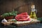 Raw beef fillet on a cutting board, thyme, olive oil. Ingredients for the preparation of stacks.