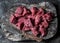 Raw beef fillet meat pieces for stew on a wooden rustic cutting board on dark background, top view