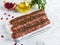 Raw beef lamb lula kebab on wooden skewer on a board, close up