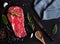Raw beef meat, uncooked steak with rosemary, lemon and spices on black