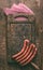 Raw beef sausages for grill or bbq on dark vintage cutting board with meet fork and napkin on rustic wooden background, top view.