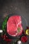 Raw beef steak on black background with cooking ingredients. Fresh beef meat