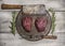 Raw beef steak on an iron pan with rosemary, meat cleaver and fork on bright, rustic wood background top view close up