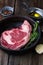 Raw beef steak marbled ribeye in a pan with rosemary, garlic and