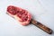 Raw beef steak on a meat cleaver on a white