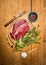 Raw beef steak with meat fork, fresh herbs an spoon of salt on rustic wooden background