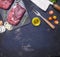 Raw beef steak with rosemary,butter and meat fork on dark rustic cutting board, top view with space for text