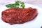 Raw beef steak with spices and Leaves of coriander on white plate. Ready for cooking.